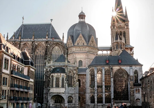 Aachener Dom mit historischen Gebäuden und Sonnenstrahlen über der Altstadt