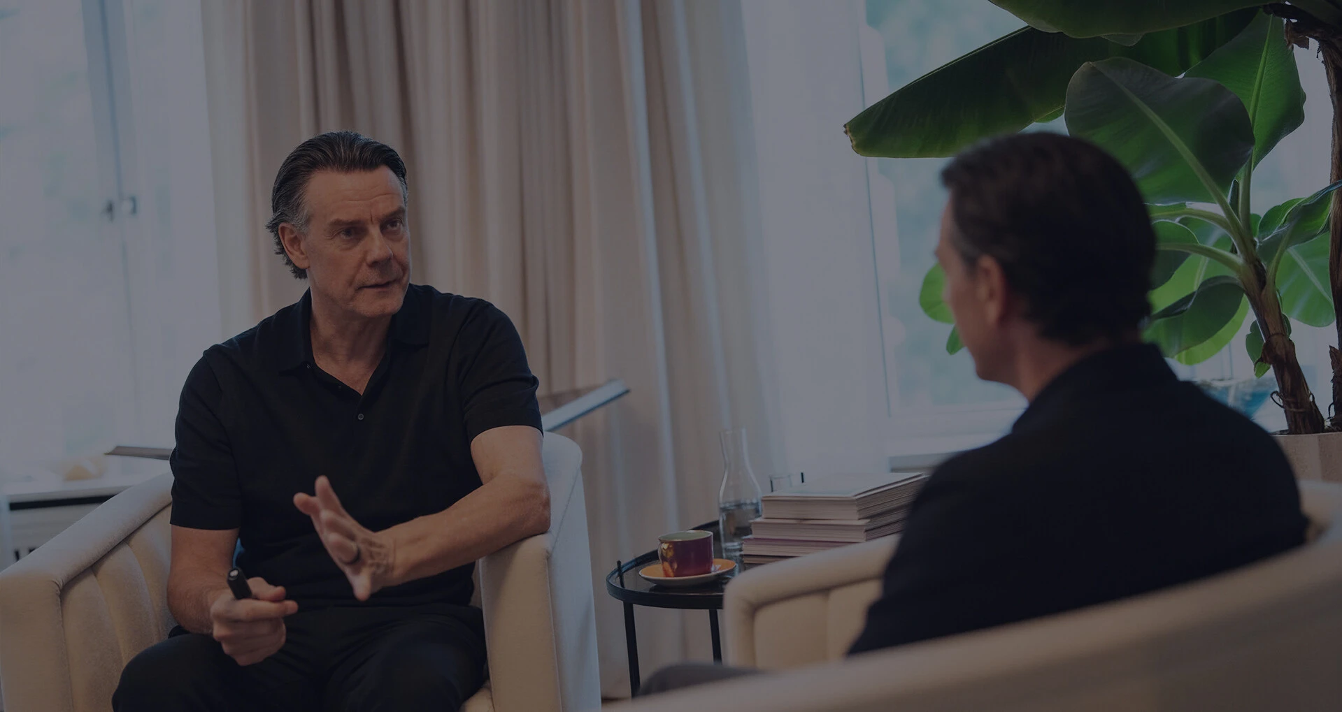 Zwei Männer sitzen sich in einem hellen Raum gegenüber und führen ein Gespräch in einer Coaching- oder Beratungssituation