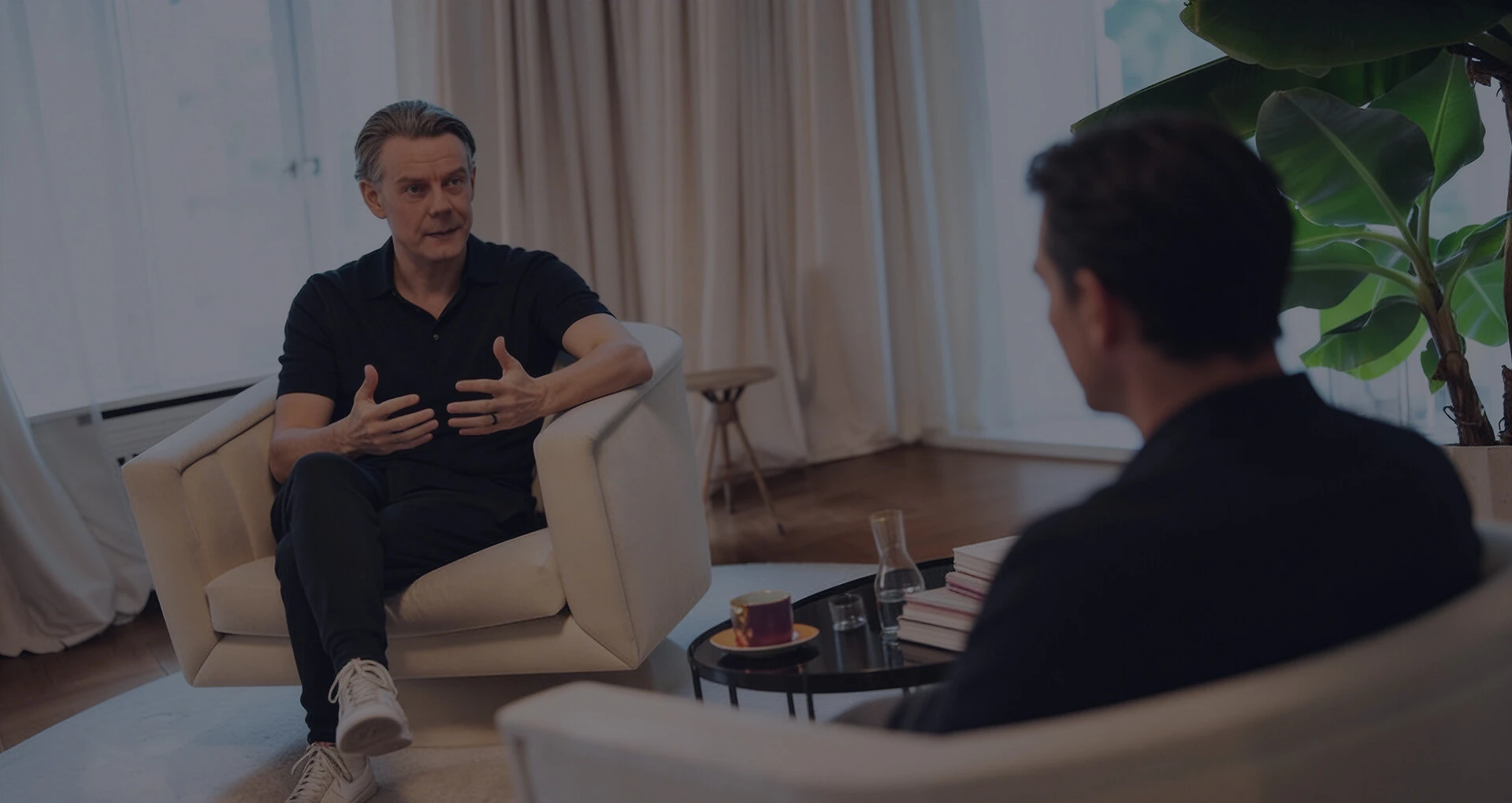 Zwei Männer sitzen sich in einem hellen Raum gegenüber und führen ein Gespräch in einer Coaching- oder Beratungssituation