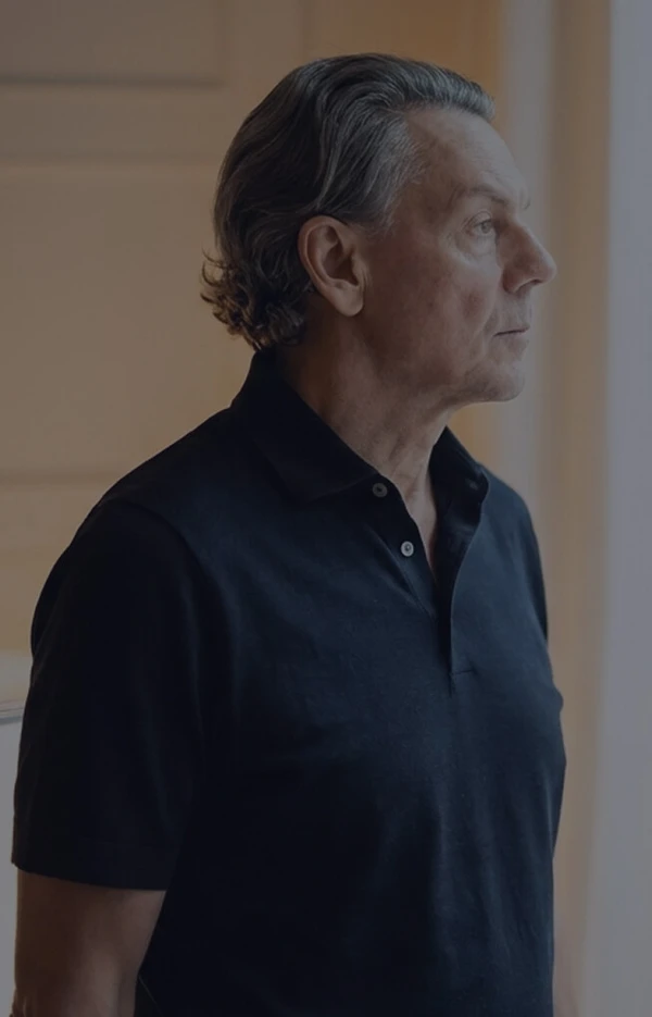 Mann steht nachdenklich am Fenster und blickt nach draußen in ruhiger Atmosphäre